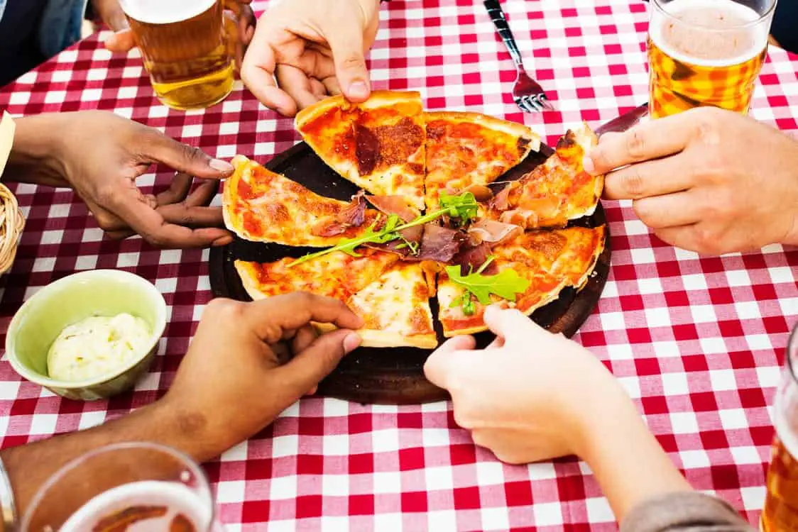 people holding a slice of pizza with beer