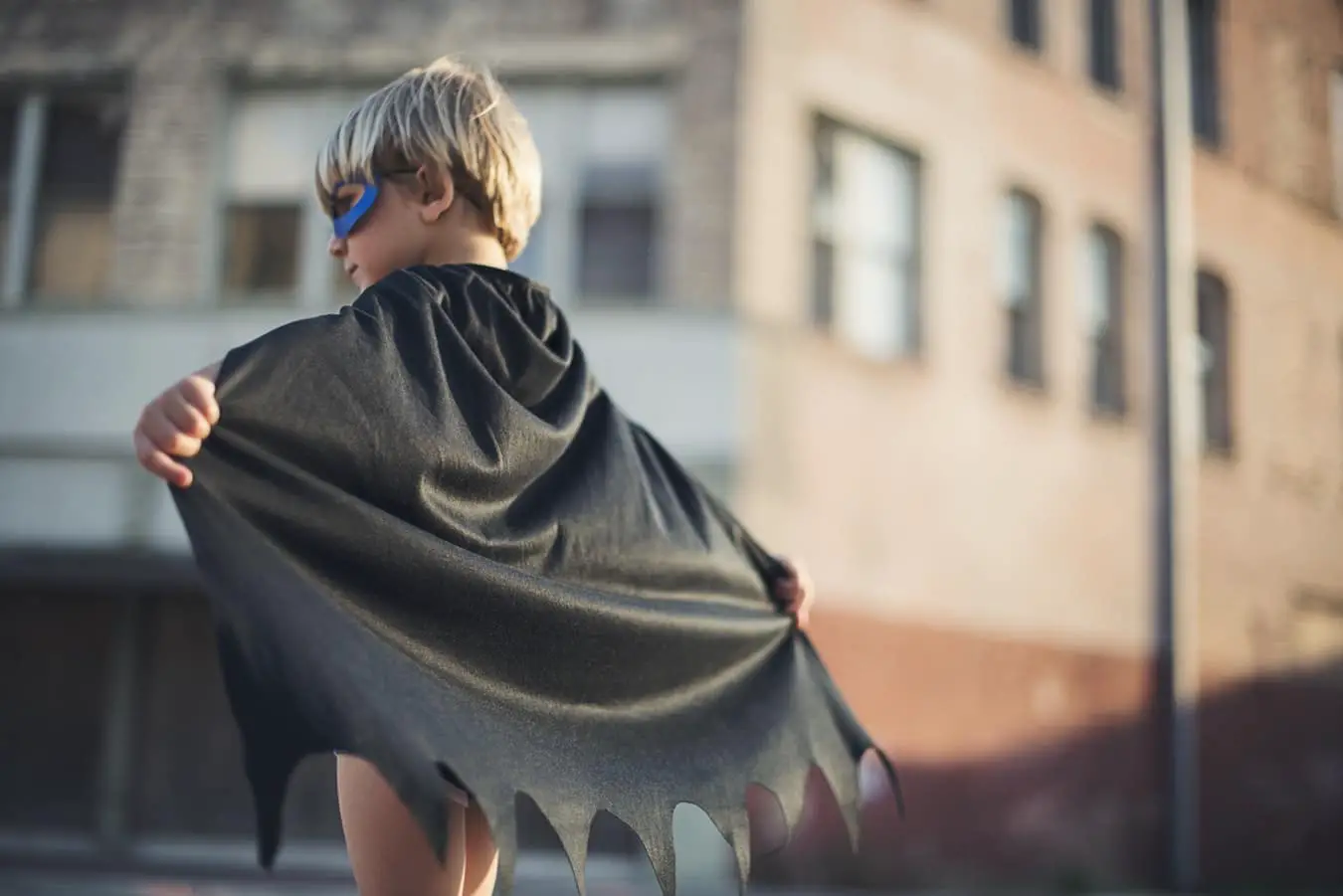 boy in a superhero costume with cape and mask