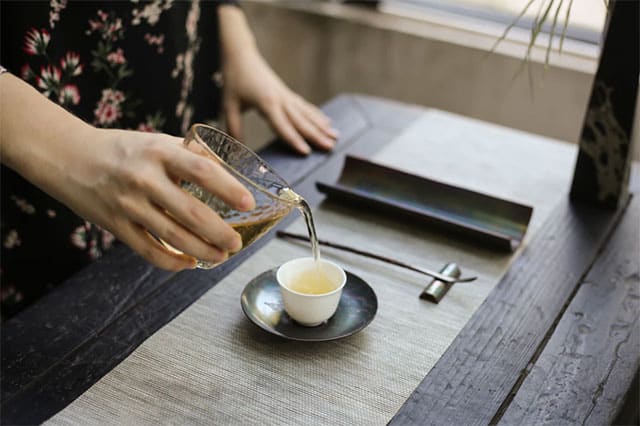 Woman pouring tea on white cup