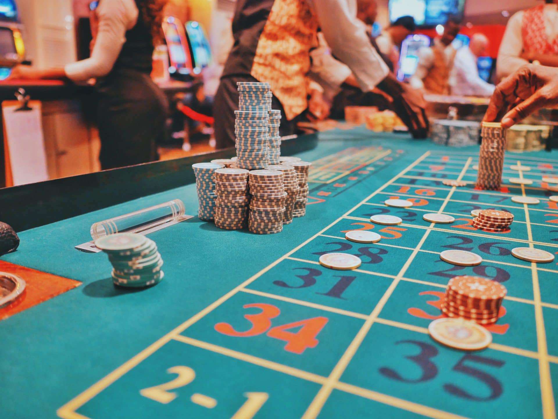 People playing at the casino and in front of them is a bet table with a lot of casino chips