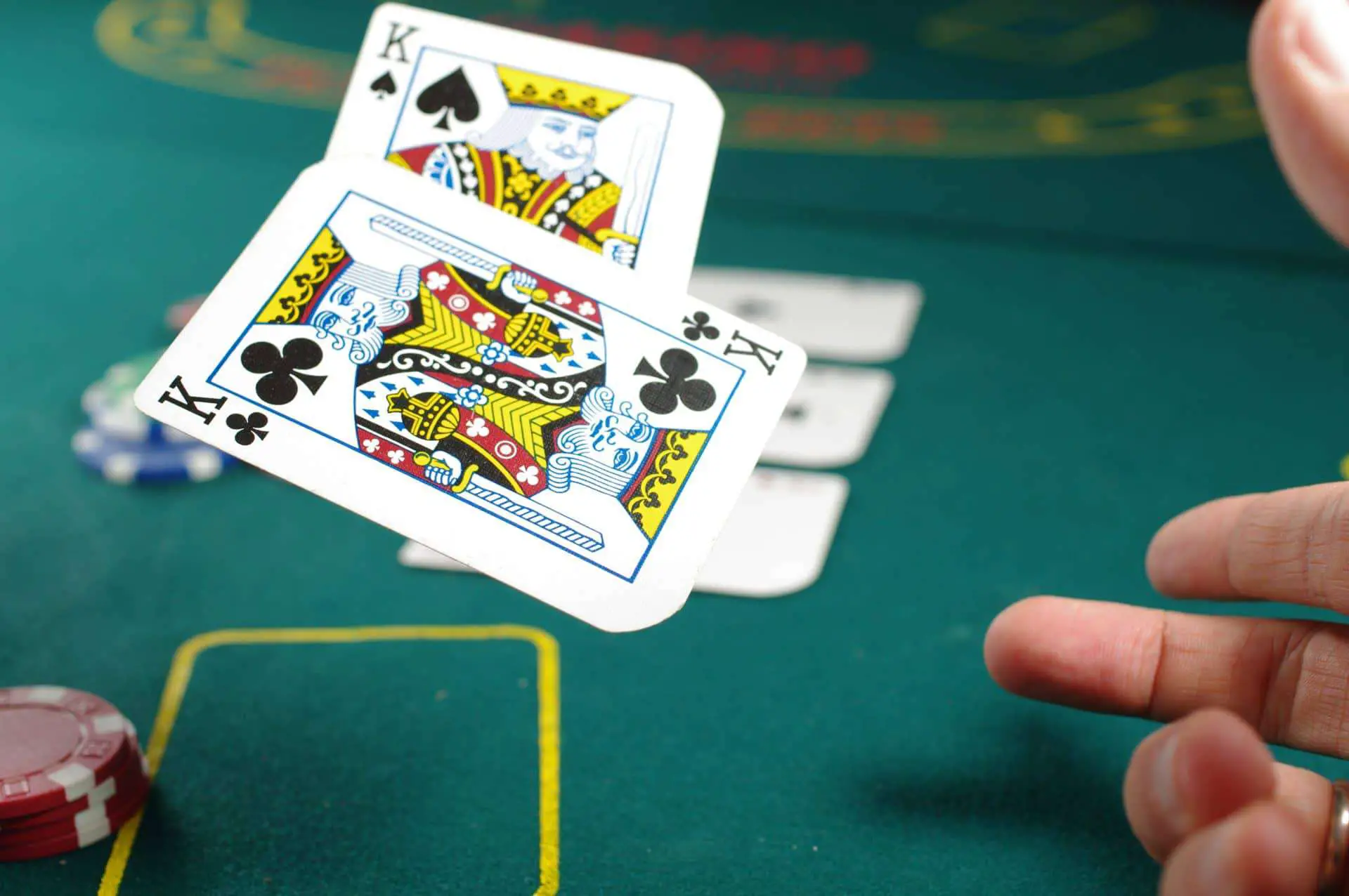 Man's hand while throwing a 2 pair of black king cards