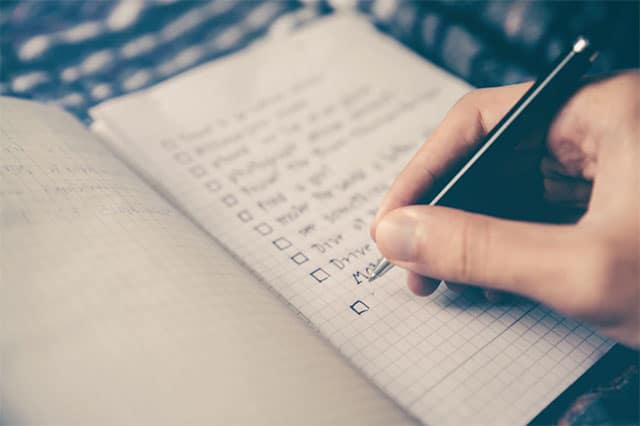 person writing bucket list on book