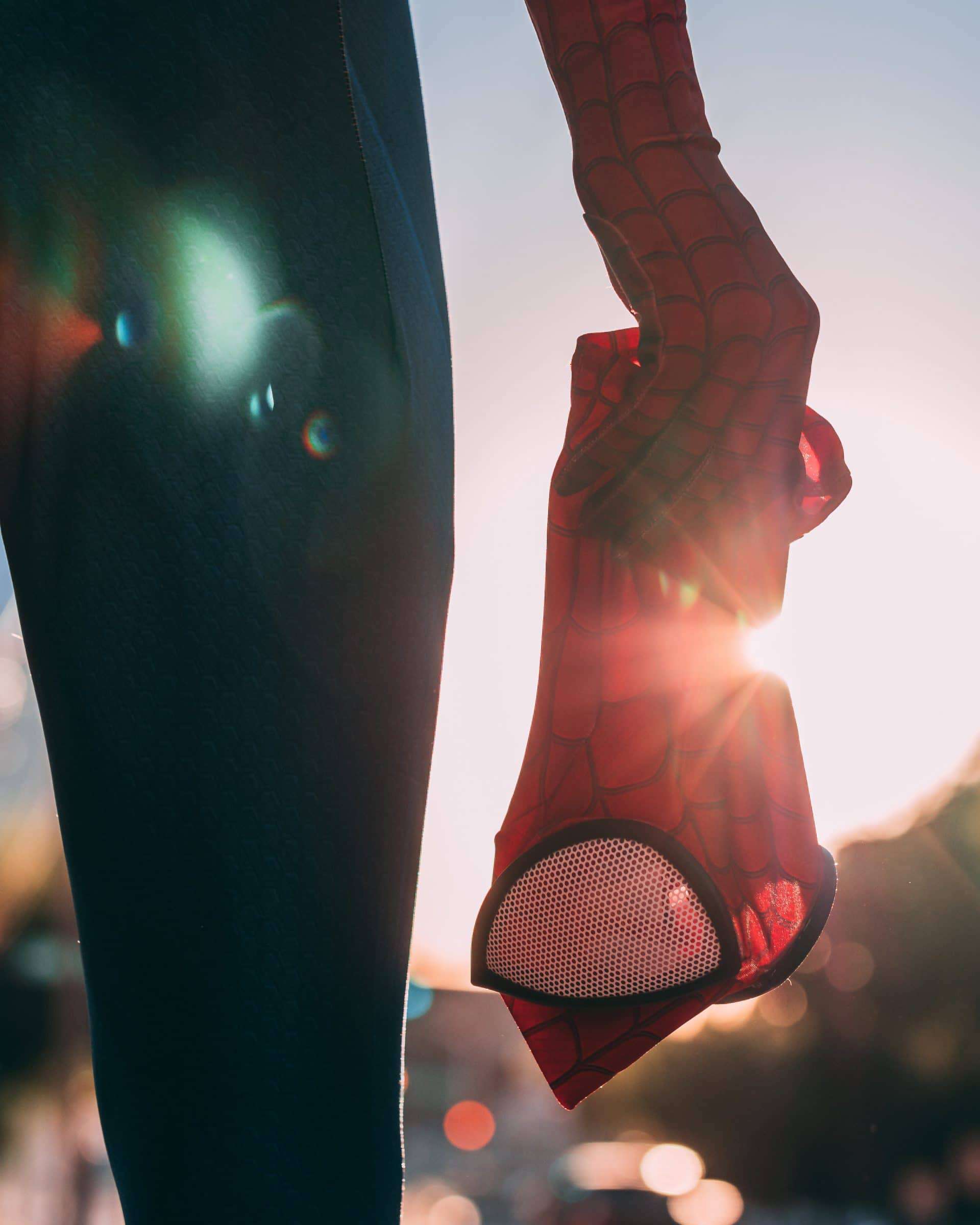 Man wearing a spider man costume and he is holding his spider man mask