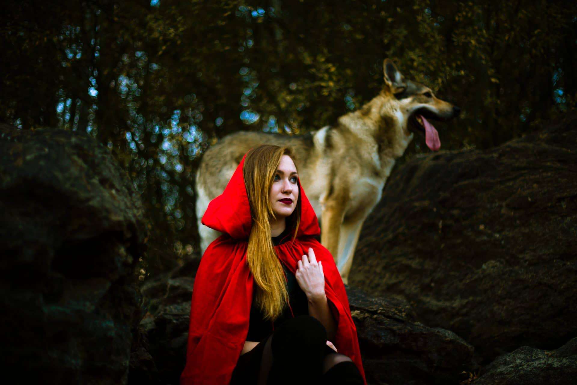 Women wearing a red hoodie cape and at her back is a dog